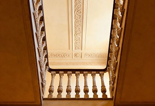 Потолок с лепниной и декоративные перила с балясинами, создающие выразительную вертикальную композицию интерьера