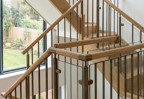 Современная лестница 2026 года с круглыми деревянными поручнями и металлическими балясинами