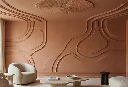 Тёплая гостиная с полиуретановой лепниной: крупные молдинги образуют плавные рельефные линии на стенах, монохромная терракотовая отделка и мягкая современная мебель.