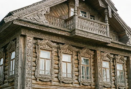 Дом украшен резьбой по дереву: ажурные наличники, резной карниз и традиционный фасад деревянного зодчества