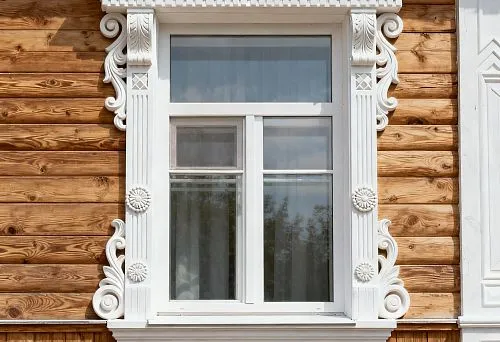 Фасадный декор для наружной отделки окна с белыми резными элементами на деревянном доме