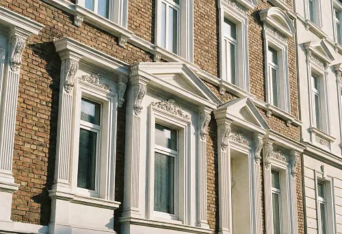 фасадные окна с декоративными обрамлениями из полиуретана на кирпичном доме