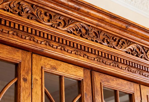 Резной деревянный погонаж с орнаментом в русском стиле над дверцами шкафа из натурального дерева
