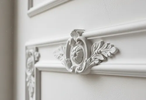 Крупный план лепнины из полиуретана на стене — декоративная накладка с растительным орнаментом и плавными линиями, демонстрирующая пример реального оформления интерьера.