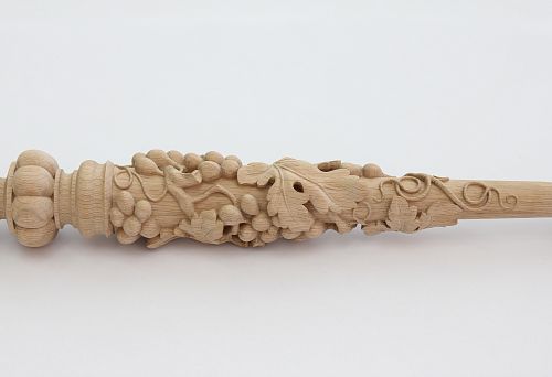 Резная балясина из светлого дерева с объёмным растительным узором и виноградными гроздьями