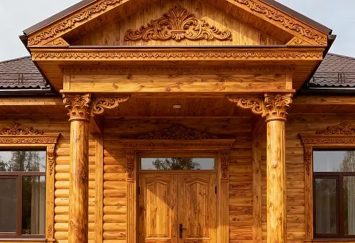 Дом с фасадным декором из дерева с резными колоннами и фронтоном