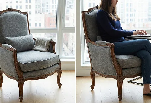 Классическое кресло-стул с резным деревянным каркасом и серой мягкой обивкой у окна